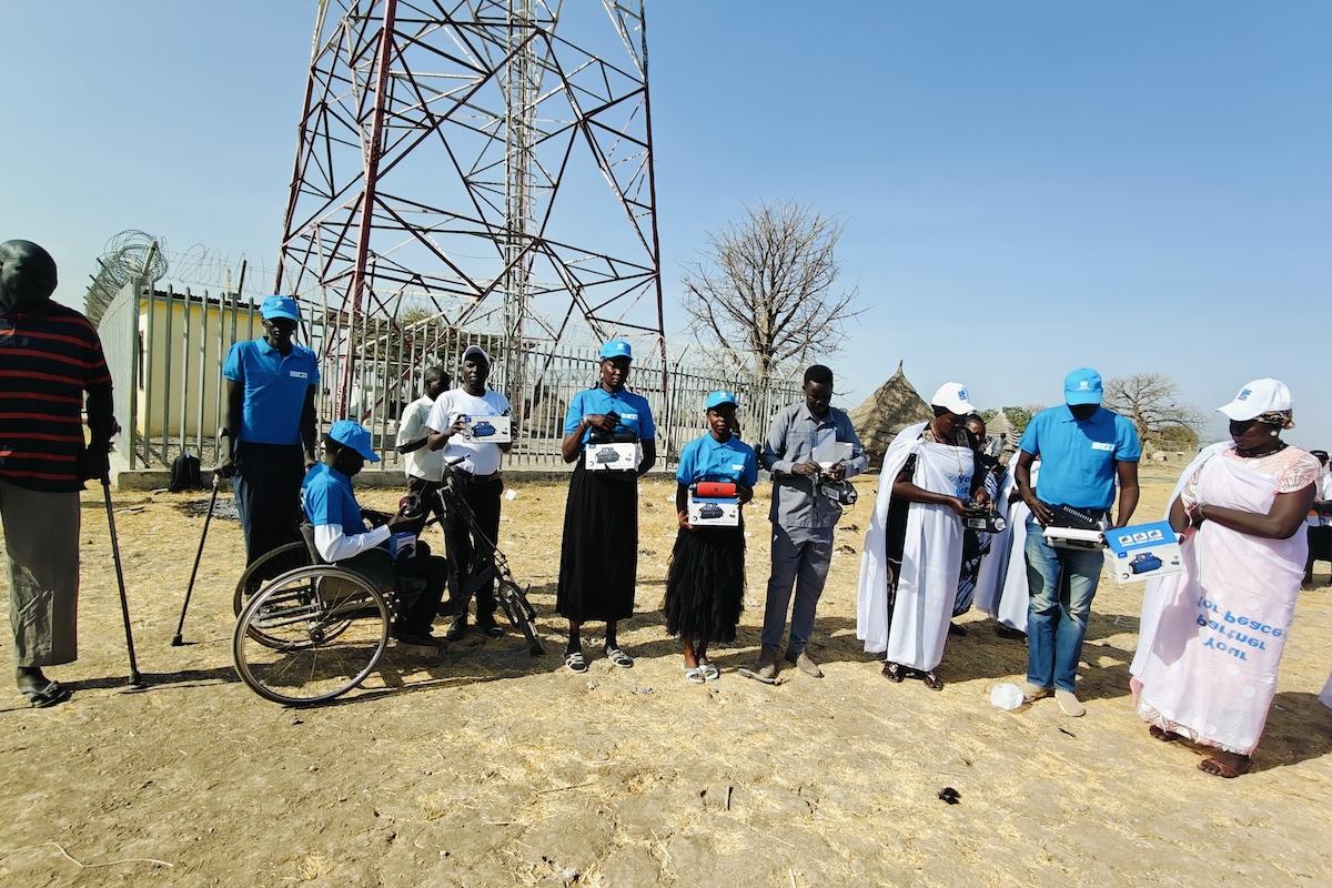 A group of people standing in front of a radio transmitting tower.